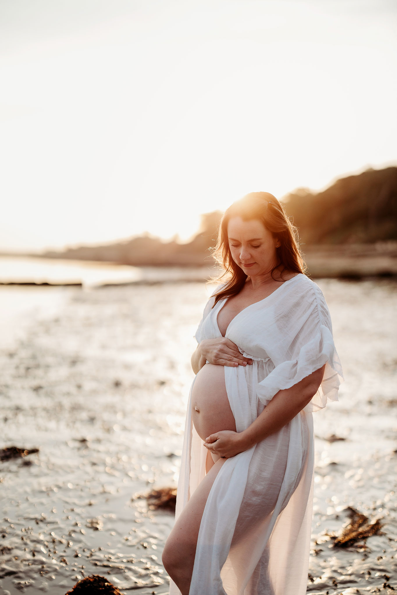 a pregnant woman at a beach having her photo taken