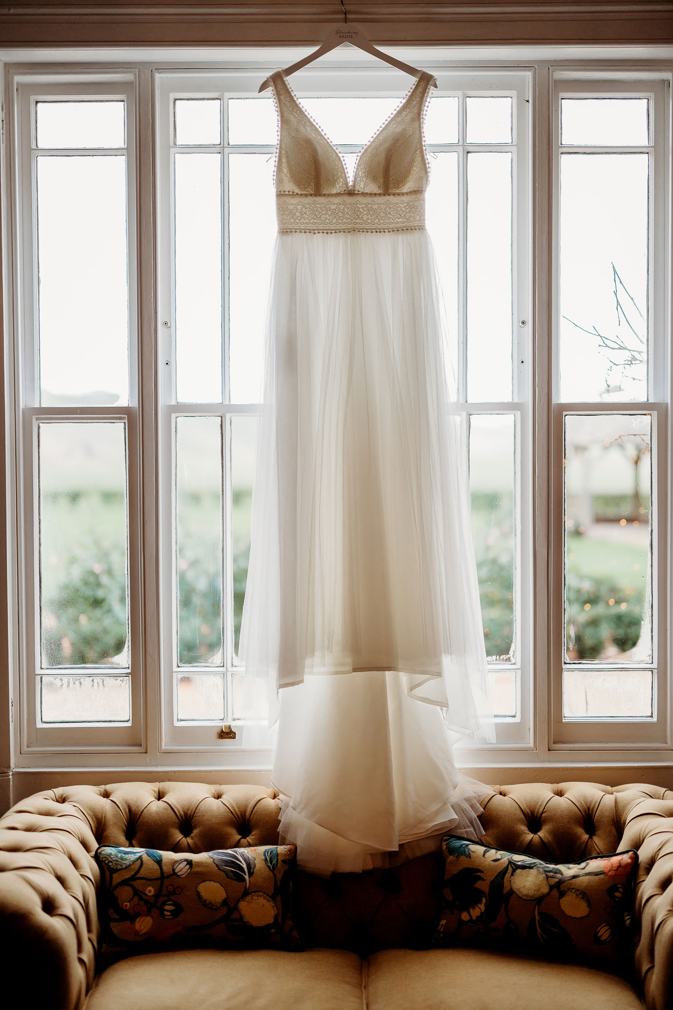 the wedding dress hung up by the victorian windows