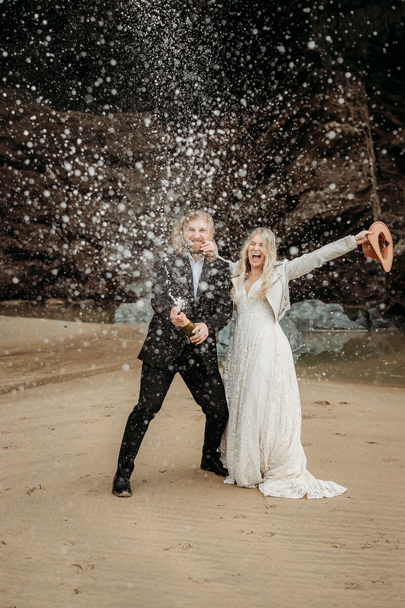 a bride and groom doing a champagne spray in Cornwall