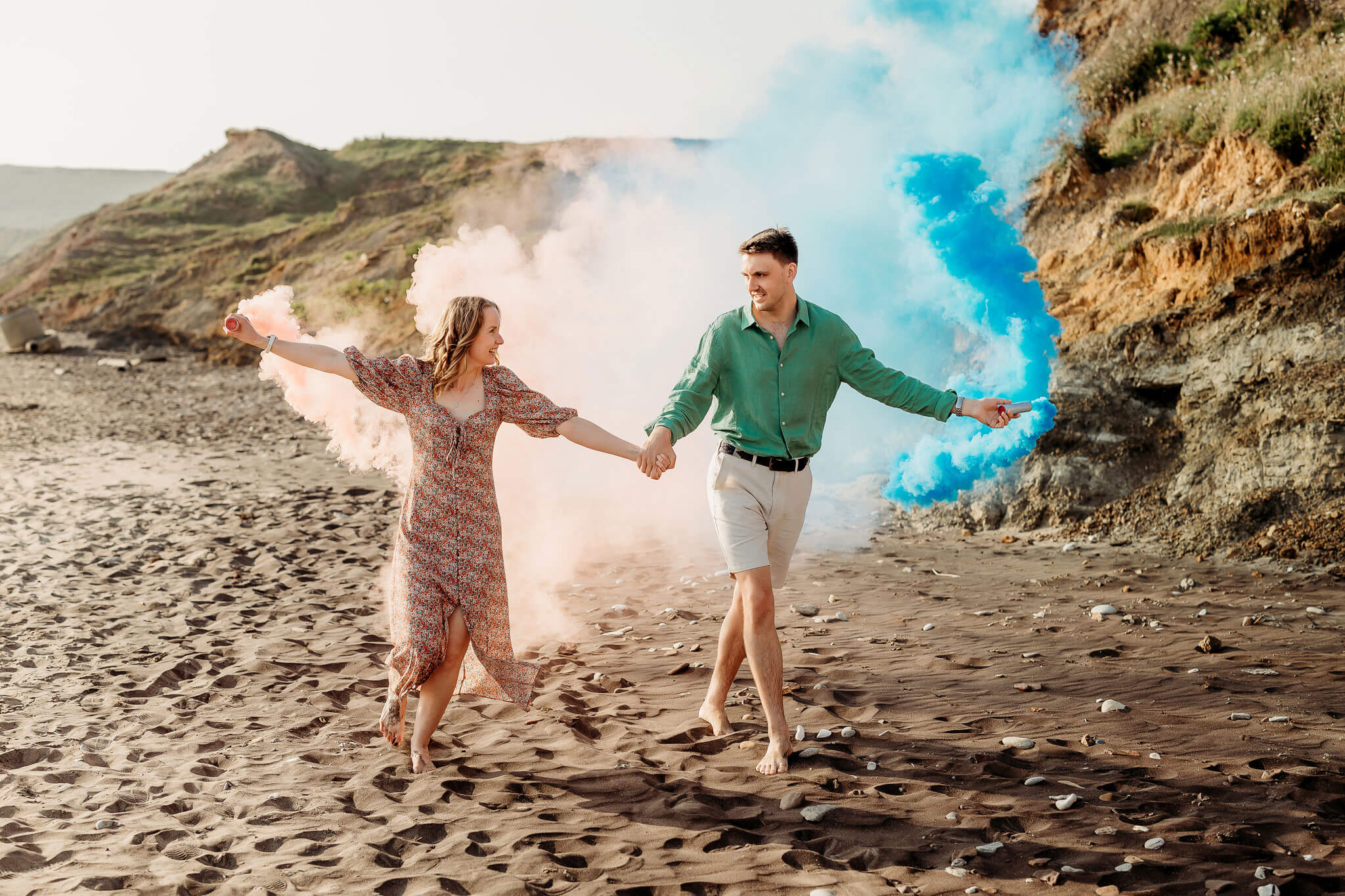 a happy engaged couple on the beach with smoke bombs