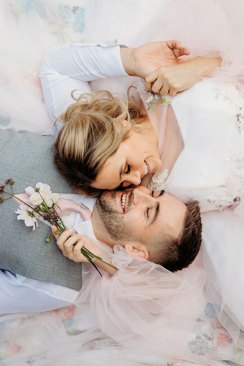 a bride and groom laying on the floor nose to nose