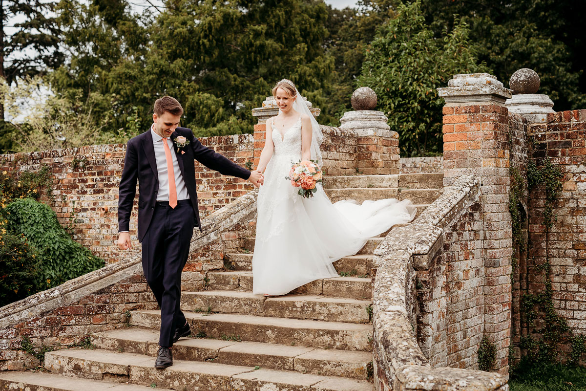 the bride and groom walking down the steps at ufton court