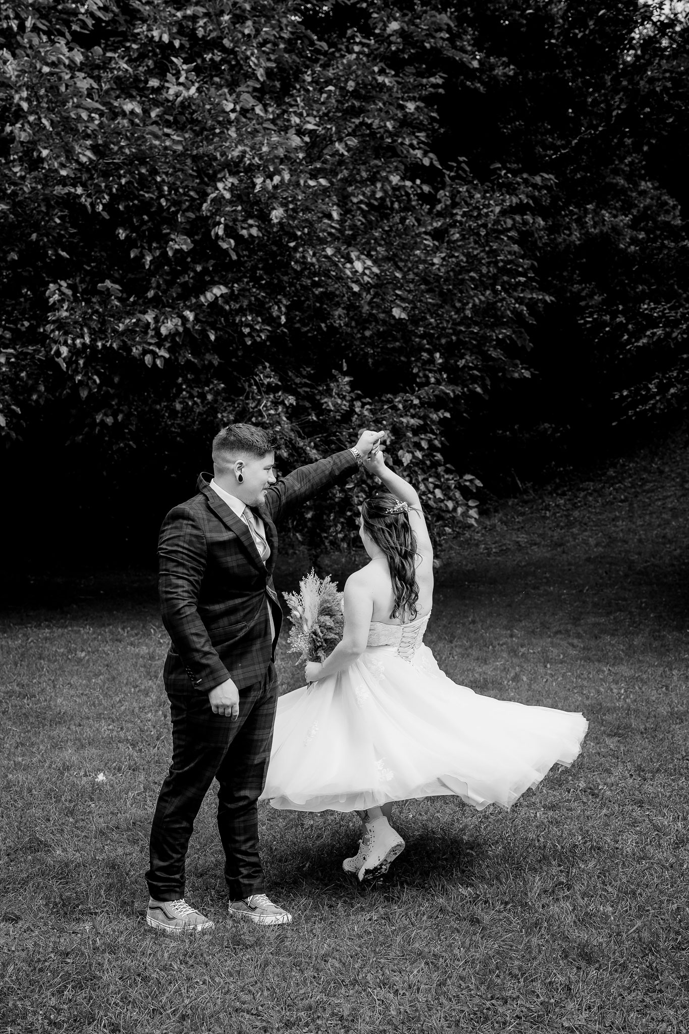 a bride and groom twirling in the park