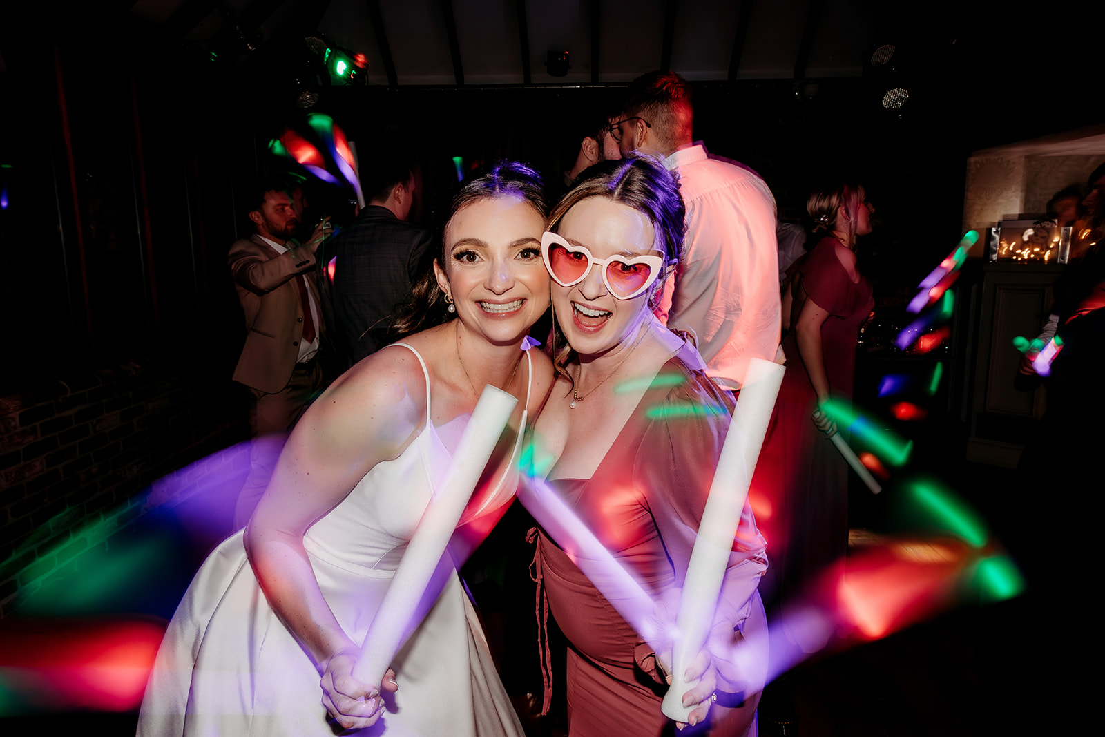 bride and her friend glow stick wedding party photos