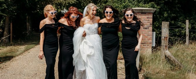 a bride and her bridesmaids laughing wearing black tie wedding bridesmaids dresses