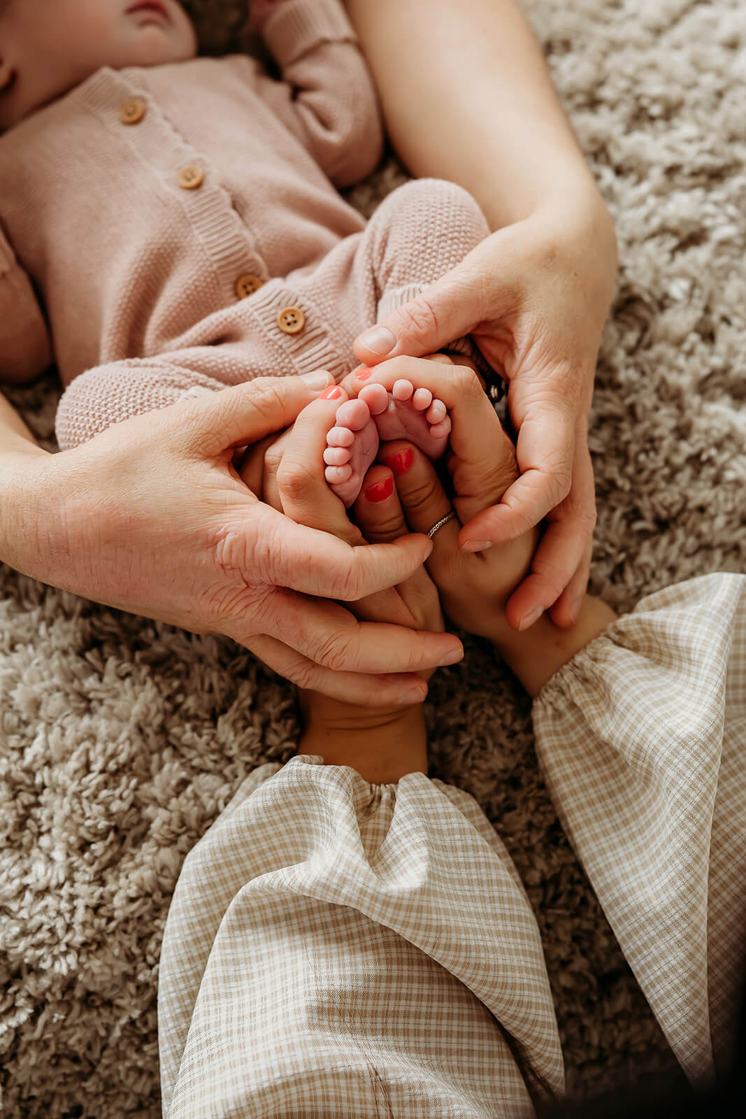 a mum and dad holding their babies feet in a bump to baby photoshoot