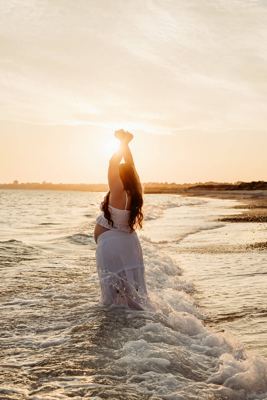 a mother to be having her maternity session at the beach in the ocean