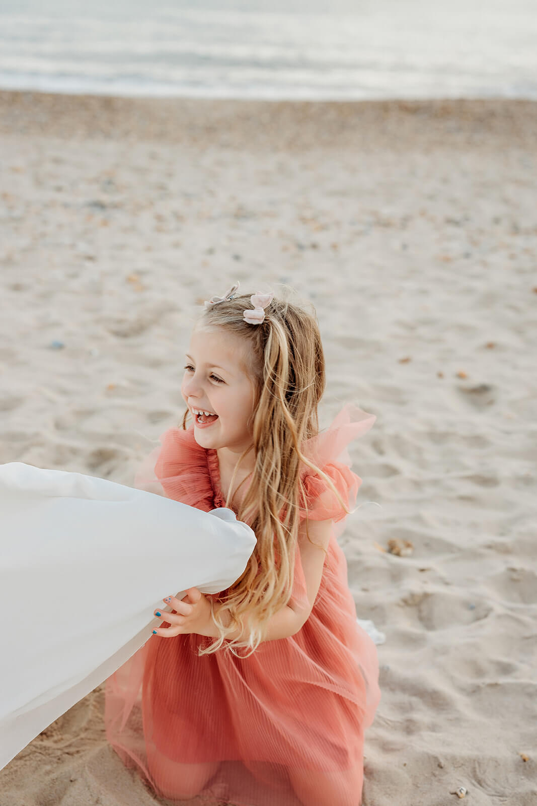 natural family photography-69 a daughter laughing naturally playing with her mums dress for a photoshoot in hampshire