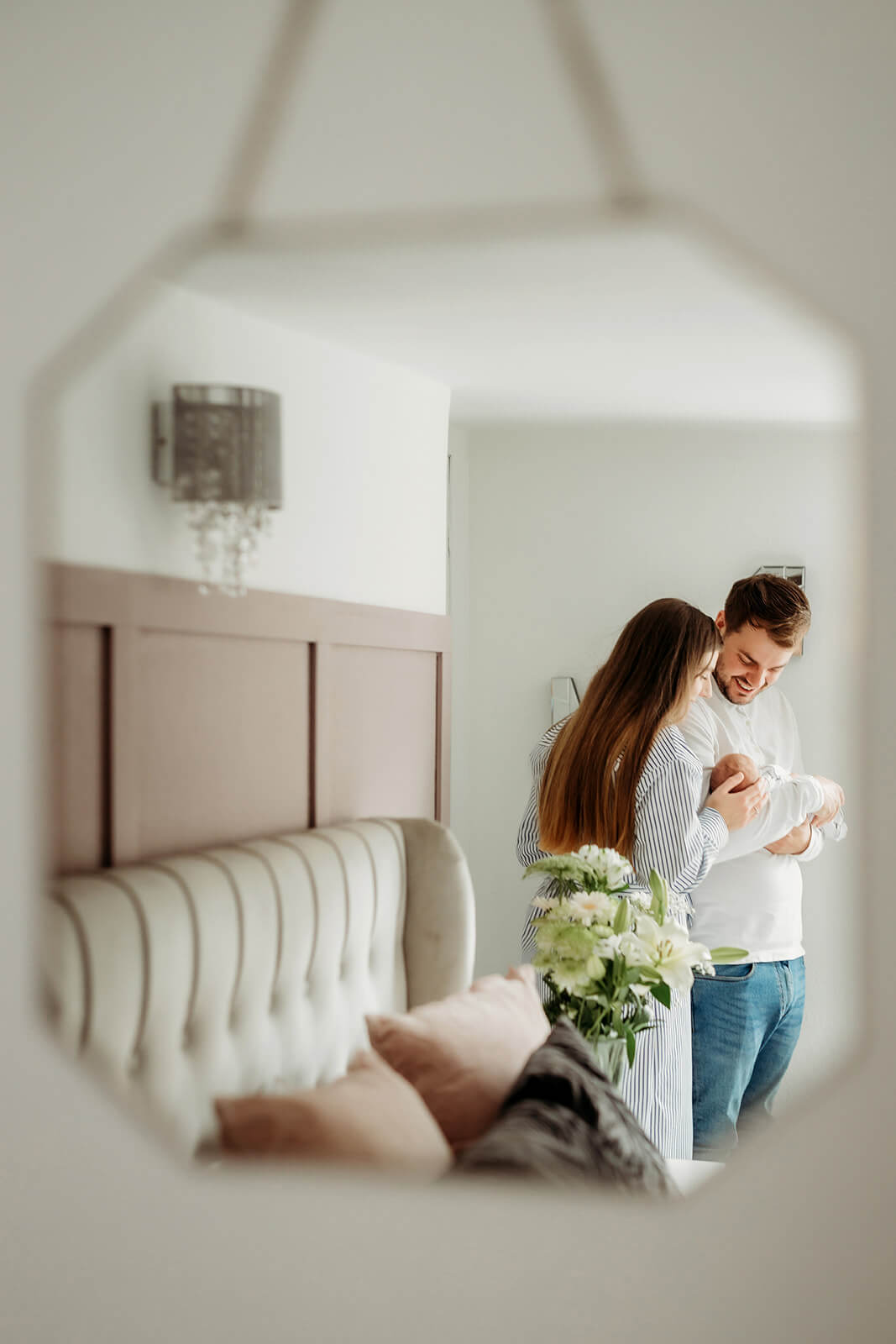 a families reflection in a mirror holding their newborn baby during a newborn photoshoot