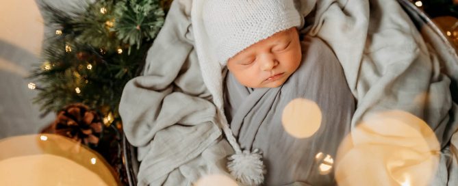 a newborn baby in a basket with fairy lights around him