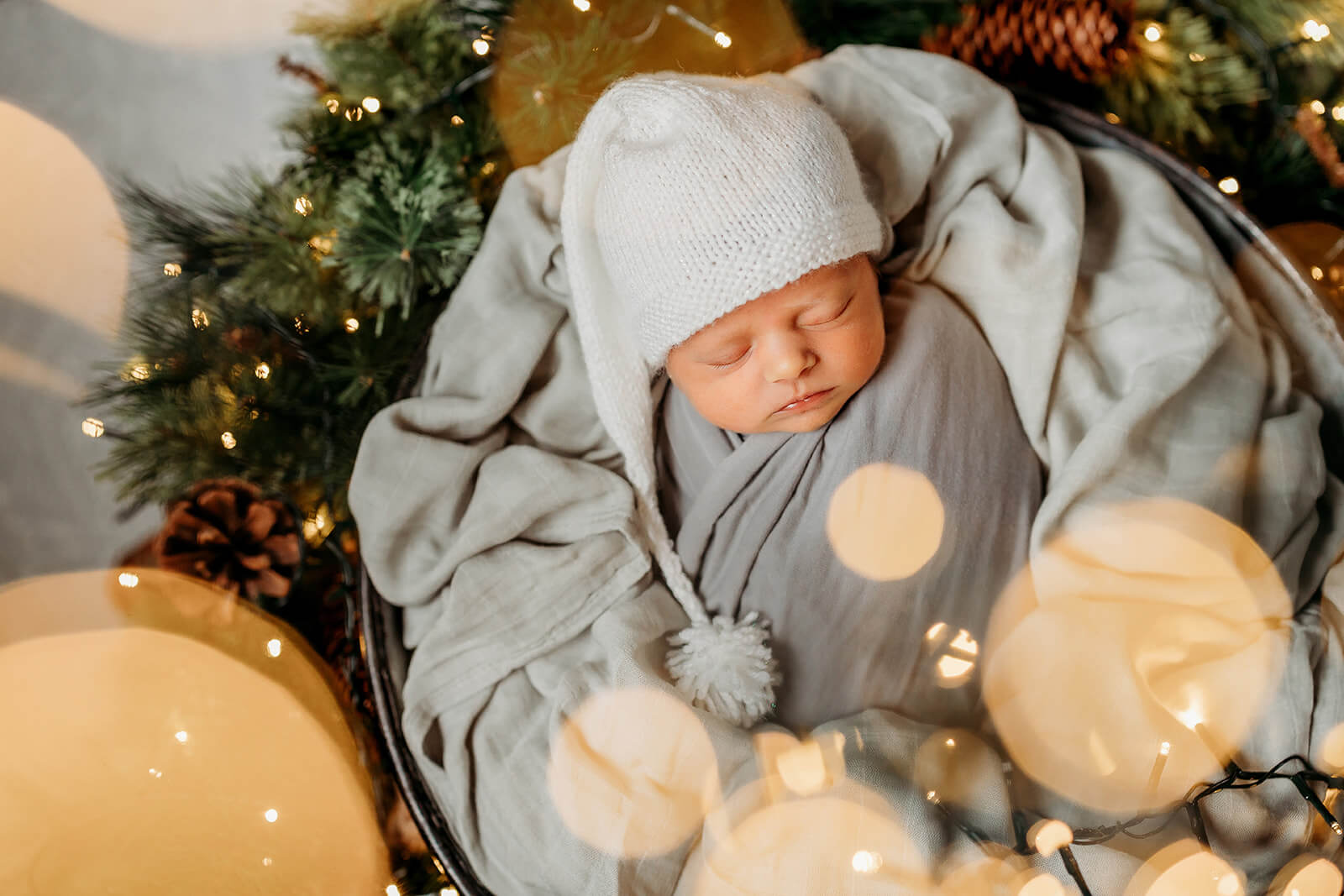 a newborn baby in a basket with fairy lights around him