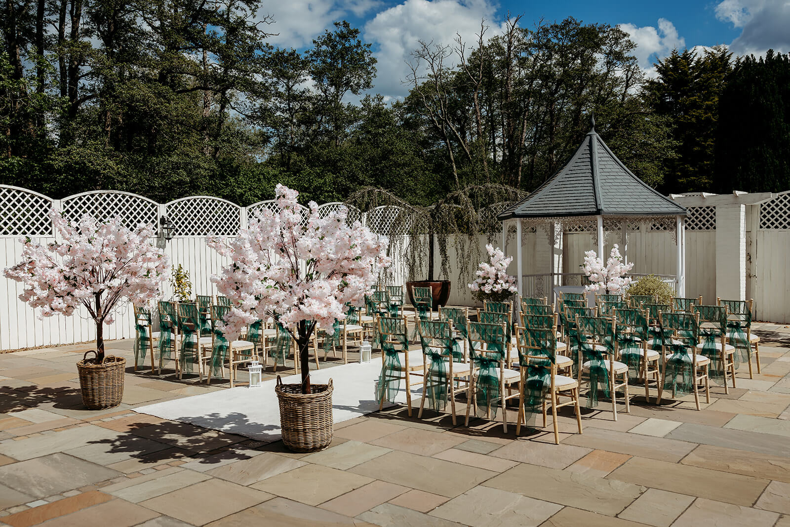 an outdoor ceremony setup with green chair ribbons
